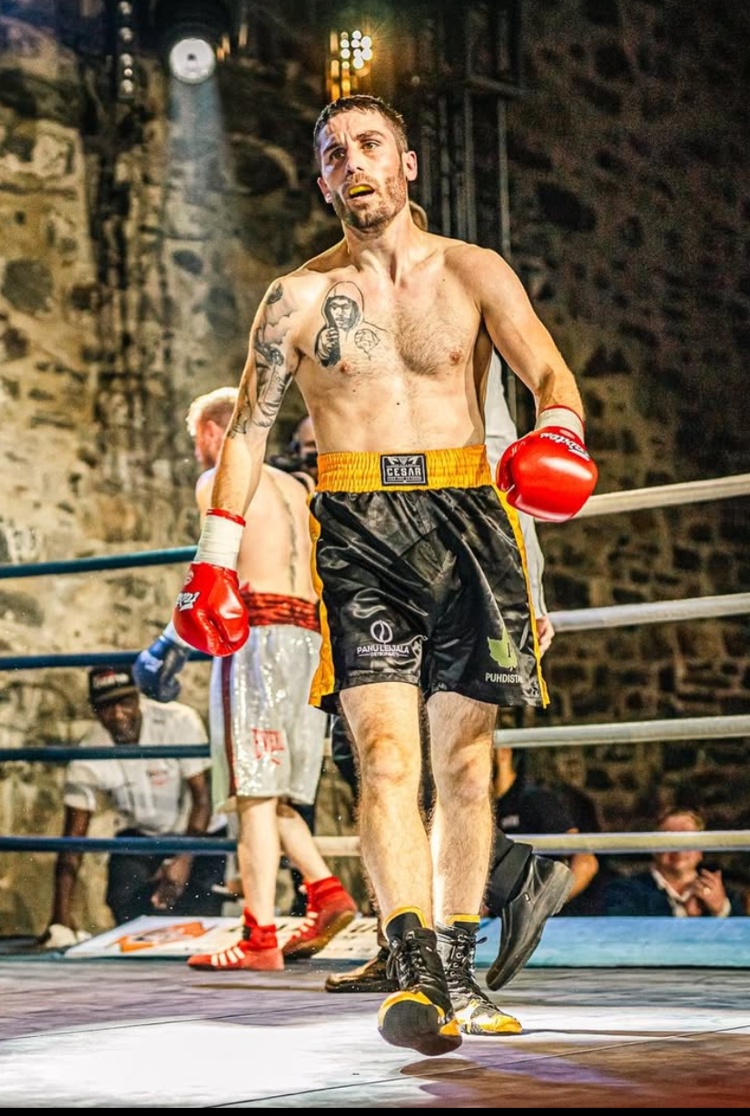 Professional boxer Rayito walking through the ring during competition wearing red gloves