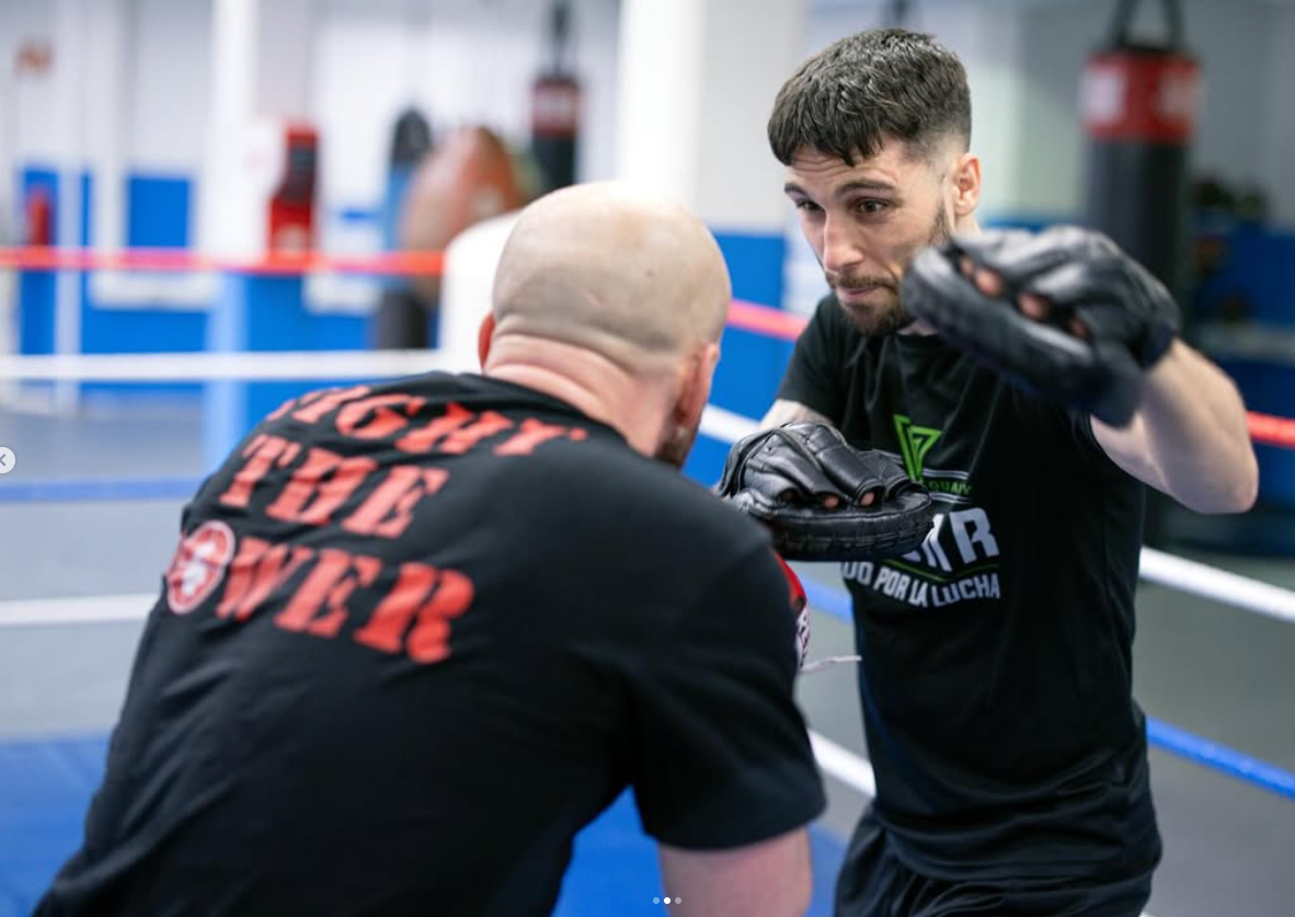 Close-up pad-work boxing training inside the ring with coach catching punches on focus mitts