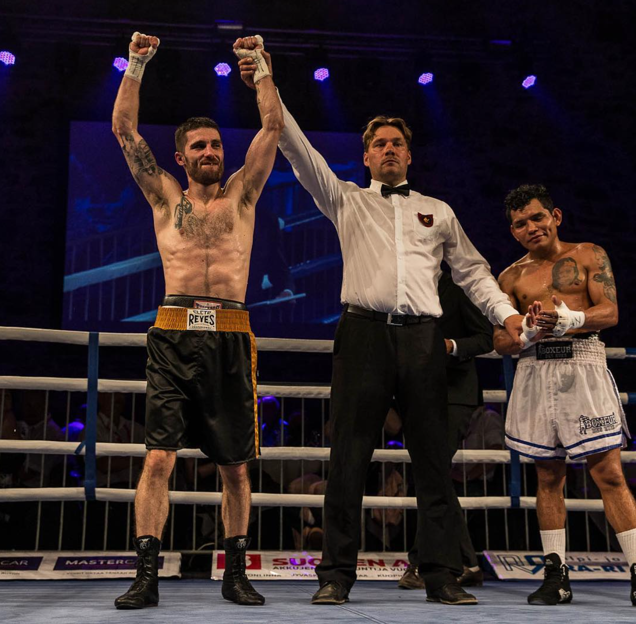 Arena referee raising professional boxer Rayito's hand in victory after a fight